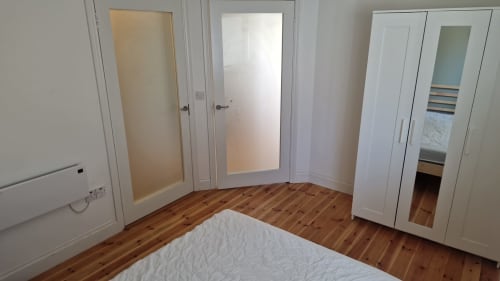 Bright bedroom with wooden floors, white wardrobes, and doors at Boswell Equestrian Centre apartment in Ashford, Ireland