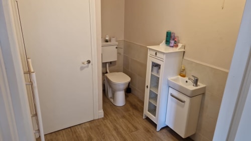 Bathroom at Boswell Equestrian Centre apartment with toilet, sink, storage cabinet, and wooden flooring