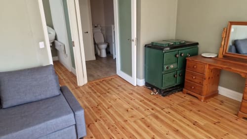 Spacious apartment living room at Boswell Equestrian Centre with wooden floors, blue sofa, green Aga stove, wooden furniture,