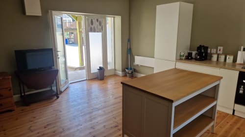 Open-plan kitchen and living area in Apt 2 at Boswell Equestrian Centre, Ashford, with wooden flooring, island counter, TV,