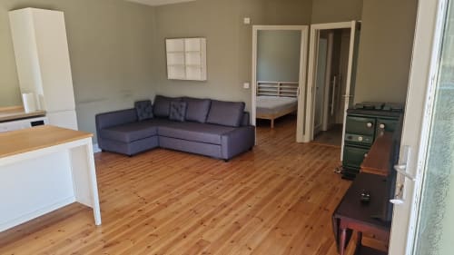 Open-plan apartment at Boswell Equestrian Centre with dark sofa, wooden floors, kitchen, and bedroom access