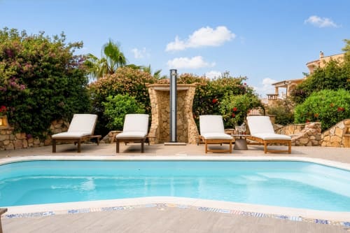 Luxury pool area at Top Villas Sardinia with lounge chairs, stone patio, and Mediterranean garden in Quartu Sant'Elena