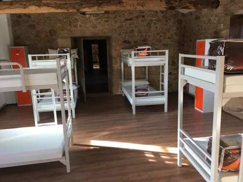 Mixed 8-bed dorm room at O Lagar De Jesus hostel in Padrón with white bunk beds and orange accents