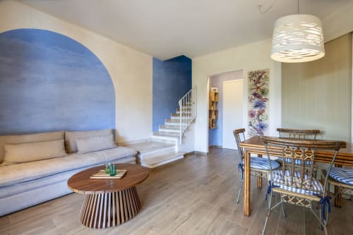 Modern villa living room with blue archway, wooden dining table, and staircase at Top Villas Sardinia in Quartu Sant'Elena