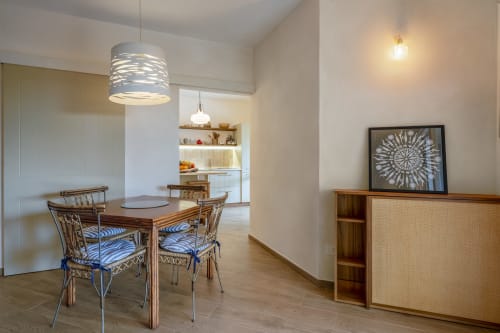 Modern dining area in Villa Tigli with wooden table, woven chairs, pendant lighting, and sea views near Quartu Sant'Elena,