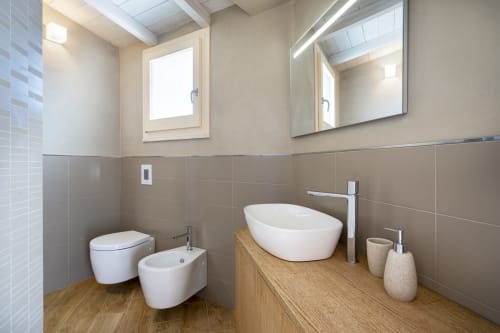 Modern bathroom with white fixtures, wooden vanity, bidet, and heated mirror at Villa Tigli in Sardinia