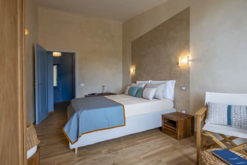 Modern villa bedroom with queen bed, blue accents, wooden furniture, and sea view at Top Villas Sardinia