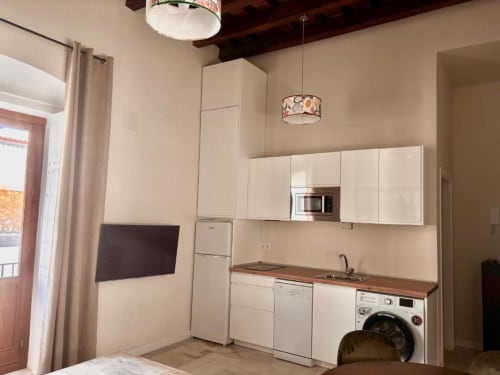 Cocina y lavadería modernas en apartamento de Jerez con muebles blancos, encimera de madera, lavadora y vistas a la ciudad