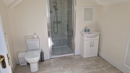Modern bathroom at Boswell Equestrian Centre with shower, toilet, sink vanity, and tiled flooring