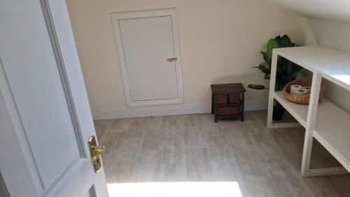 Studio apartment interior at Boswell Equestrian Centre with wooden flooring, white shelving, dark wood nightstand, and