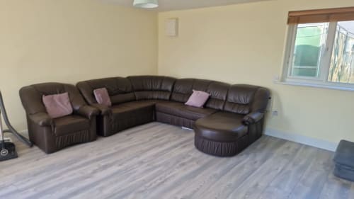 Brown leather sectional sofa with pink cushions in The Studio apartment at Boswell Equestrian Centre, Ashford