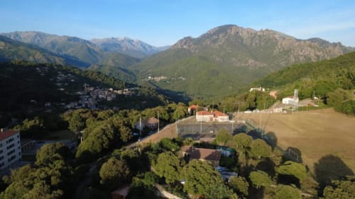 Vue aérienne de Mare e Monti à Vico (FR) avec montagnes, terrain de sports et paysage méditerranéen