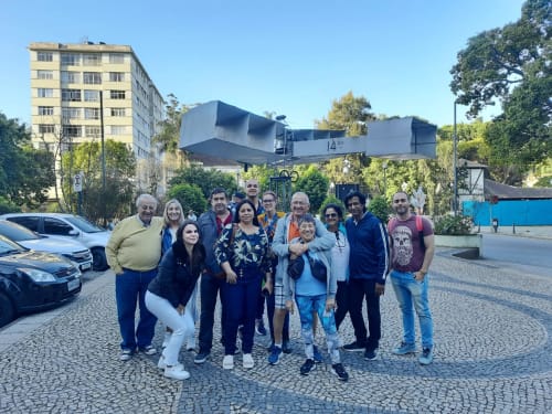 Grupo de hóspedes posando juntos no hostel Rio Vibes no Rio de Janeiro com uma icônica escultura de arte urbana acima