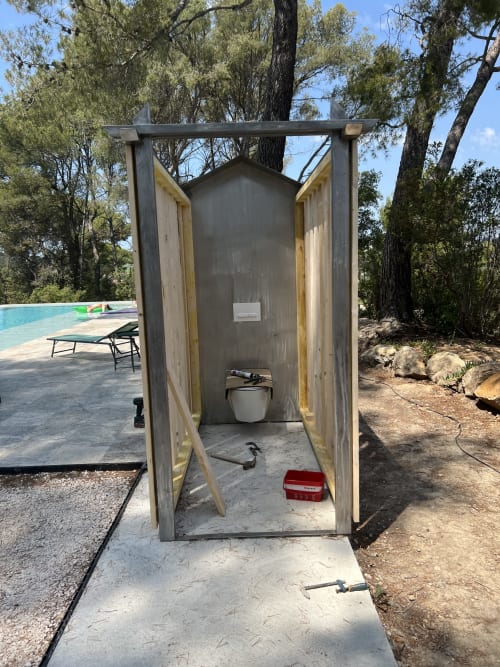 Toilettes extérieures de la maison d'hôtes Mas Misajail au Castellet, avec portes en bois et paysage désertique
