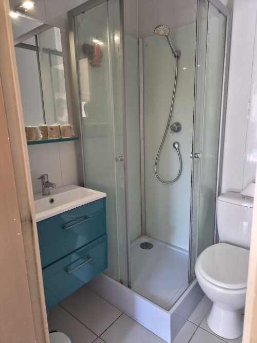 Salle de bain moderne de l'Hôtel Bar La Pinède avec vasque turquoise, douche à l'italienne, toilettes et miroir