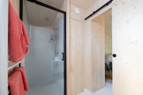 Modern bathroom with glass shower enclosure and red towels at Le chant des pins Lodges & Spas, Saint-Marc-Jaumegarde