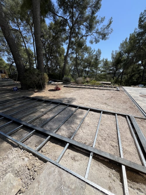 Chantier de construction du Mas Misajail B&B au Castellet avec structure métallique, sol en gravier et pins
