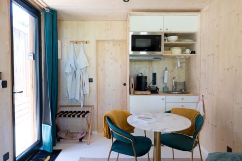 Modern wooden lodge interior at Le chant des pins with dining table, kitchenette, and teal accents in Saint-Marc-Jaumegarde