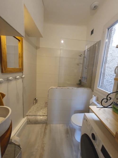 Salle de bain contemporaine dans un appartement provençal avec douche à l'italienne, toilettes et lavabo encadré d'un miroir doré