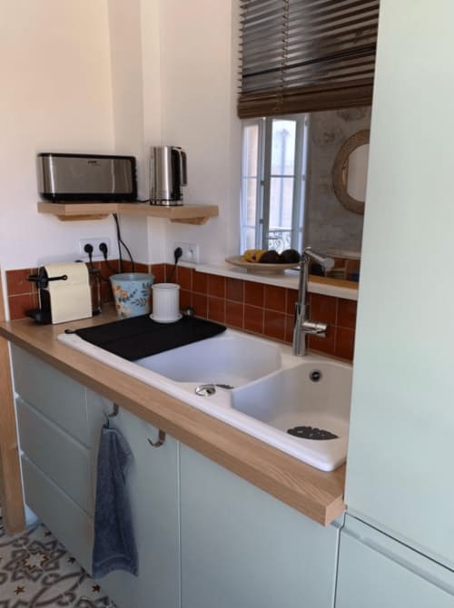 Évier de cuisine moderne à double bac, plan de travail en bois, dosseret en carrelage terracotta et robinetterie inox en Provence