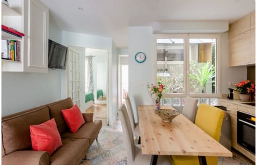 Sofisticado apartamento parisino en Saint-Germain con cocina abierta, comedor, sofá marrón y vistas al jardín