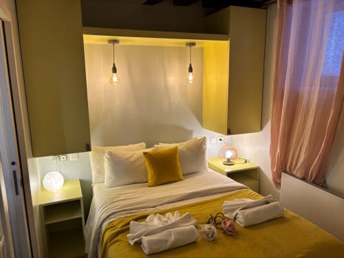 Dormitorio moderno del hotel ALDARO en Saint con acentos amarillos, iluminación colgante y ropa de cama acogedora