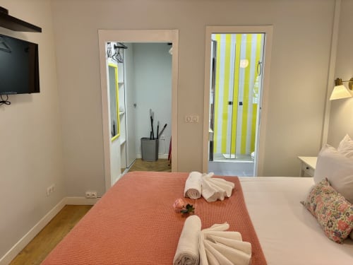 Dormitorio del apartamento Aldaro's Odéon Saint Germain en París con colcha coral, toallas y acceso al baño