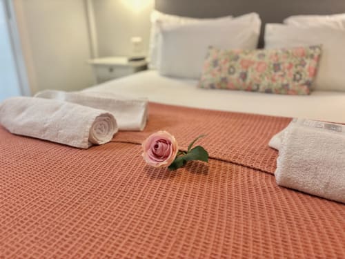 Cama de lujo en París con rosa rosa, toallas enrolladas y almohada floral - Aldaro Odéon