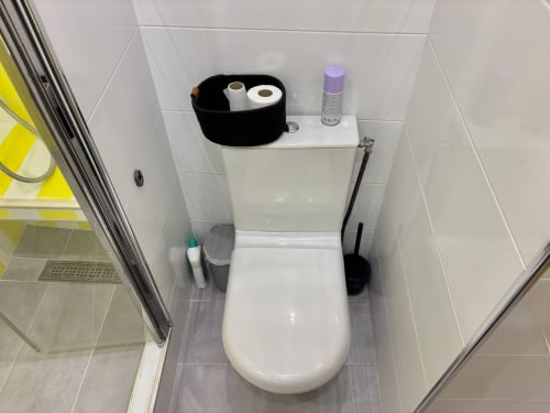Baño limpio con cesto de almacenamiento negro y ambientador púrpura en el apartamento ALDARO París