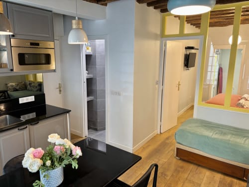 Cocina y dormitorio del apartamento Aldaro Paris en Odéon Saint Germain, con flores en la encimera y cama visible