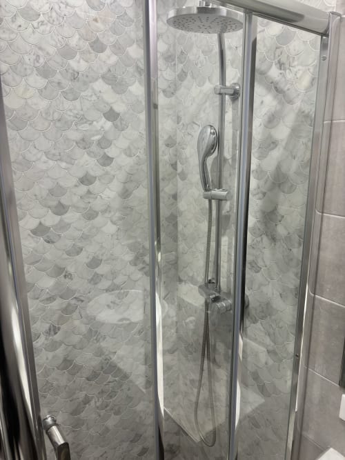 Elegante duchas con azulejos de mármol, alcachofa lluvia y ducha de mano en apartamento Aldaro Paris