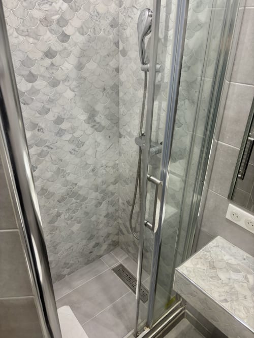 Ducha moderna con azulejos de escama de pez en mármol y cristalera, apartamento Aldaro París