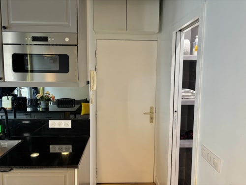 Cocina moderna con horno de acero inoxidable y encimeras negras en apartamento Aldaro Odéon Saint Germain en París