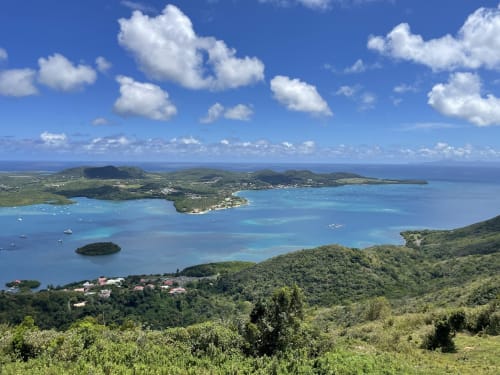 Vue aérienne de la baie turquoise avec collines verdoyantes, voiliers et village côtier près de Le Marin, Martinique