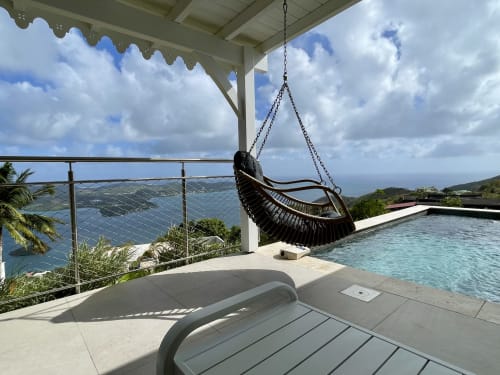 Terrasse de villa avec vue océan, chaise suspendue noire, piscine à débordement et vue sur la mer des Caraïbes
