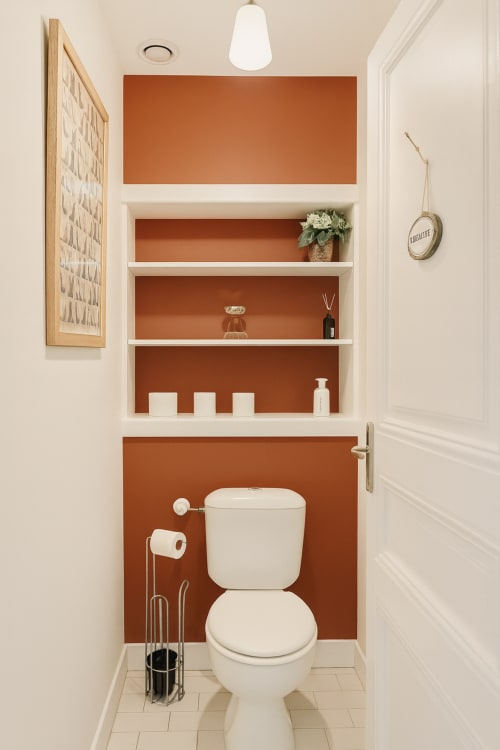 Salle de bains moderne de la Suite Citybreak Maunoury à Chartres avec toilettes blanches, panneaux muraux couleur rouille et étagères flottantes