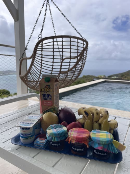 Petit-déjeuner tropical sur fauteuil suspendu surplombant la piscine et l'océan à la villa Terrasses du Morne Gommier, Martinique