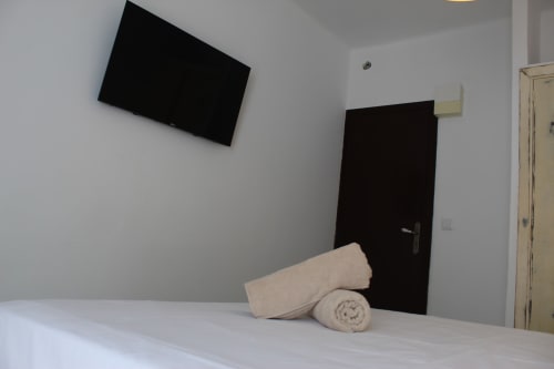 Habitación moderna de hostal en Villa Palmer, Paguera, con TV de pared, toallas enrolladas en la cama y puerta negra