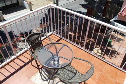Balcón del hostel Villa Palmer en Paguera con mesa, sillas y vistas al mar sobre la ciudad
