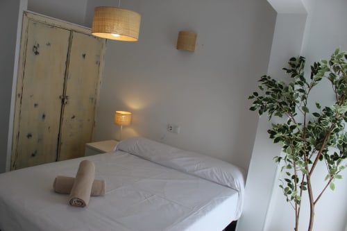 Dormitorio doble moderno en la Villa Palmer hostel de Paguera con ropa de cama blanca, lámparas colgantes de mimbre y planta en maceta