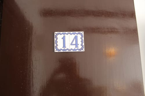 Placa de la habitación 14 en pared marrón del albergue Villa Palmer en Paguera
