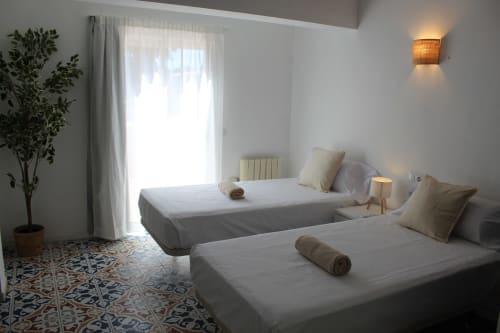 Habitación doble en Villa Palmer hostel en Paguera con dos camas, sábanas blancas, planta en maceta y acceso a balcón
