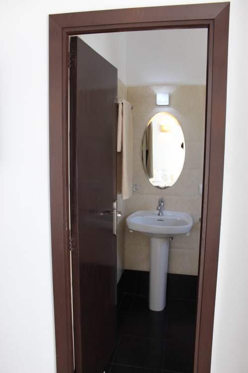 Baño moderno en Villa Palmer hostel de Paguera con lavamanos de pedestal, espejo ovalado y cabina de ducha