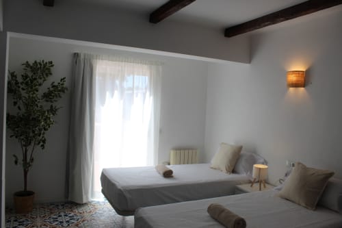 Dos camas individuales en luminosa habitación doble de Villa Palmer hostel, Paguera con puertas a balcón y comodidades modernas