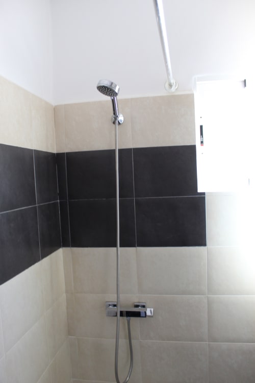 Baño moderno con ducha y azulejos en tonos negro y beige en el hostal Villa Palmer de Paguera
