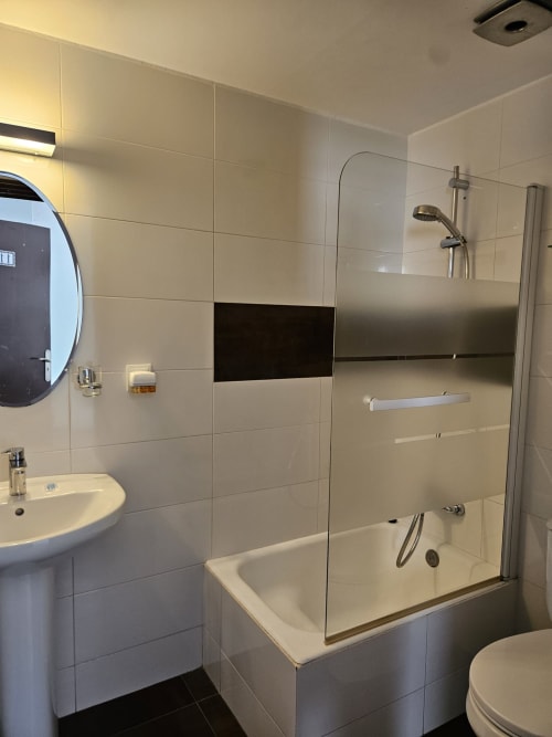 Baño moderno en Villa Palmer hostel en Paguera con ducha, lavamanos pedestal y paredes con azulejos beige