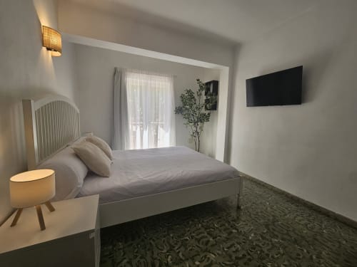 Moderno dormitorio doble con balcón en Villa Palmer hostel en Paguera, con cama blanca, TV de pantalla plana y diseño contemporáneo