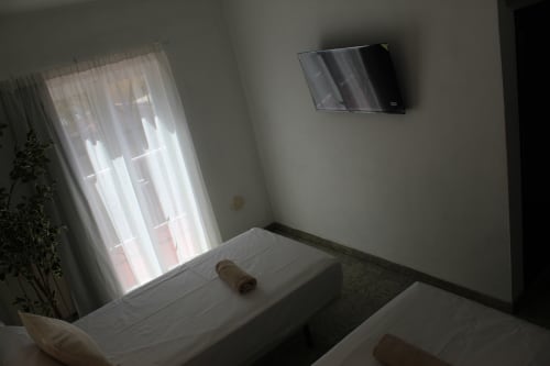 Moderna habitación doble en Villa Palmer hostel de Paguera con camas gemelas, TV de pared y balcón con luz natural
