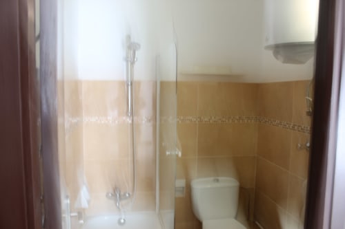 Baño de la Villa Palmer hostel en Paguera con azulejos beige, cabina de ducha e inodoro