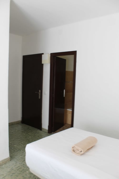 Moderna habitación doble en Villa Palmer hostel en Paguera con cama, puertas de madera oscura y paredes blancas